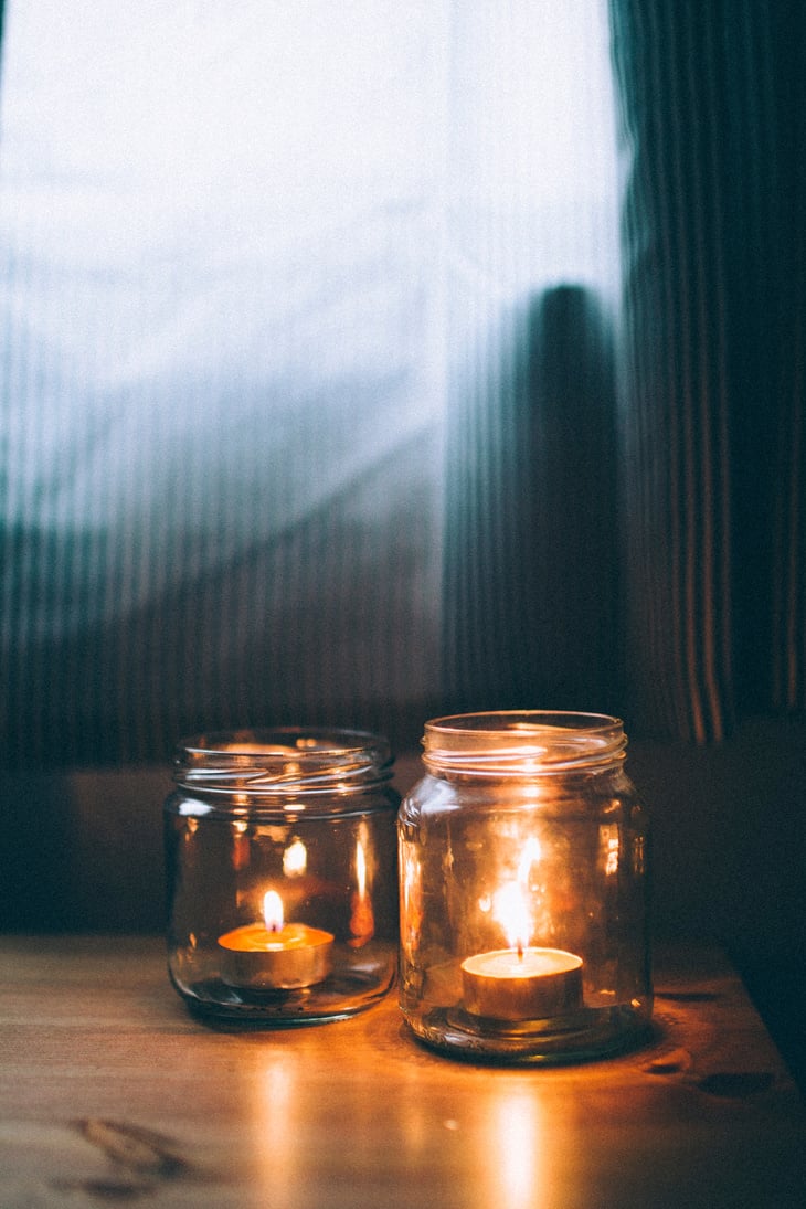 Two Lighted Jar Candles on Top Brown Wooden Table